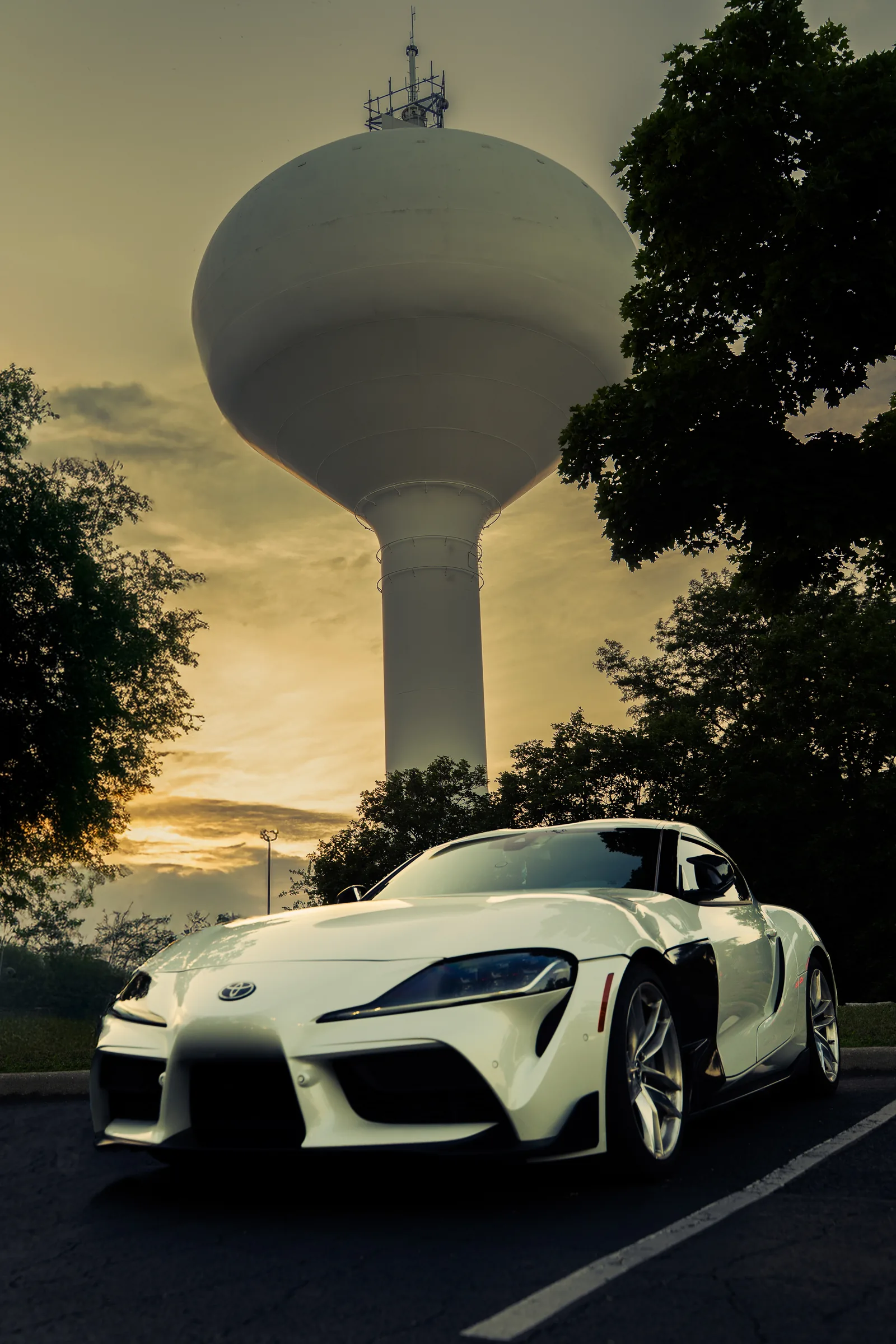 White Toyota Supra at sunset beneath a water tower